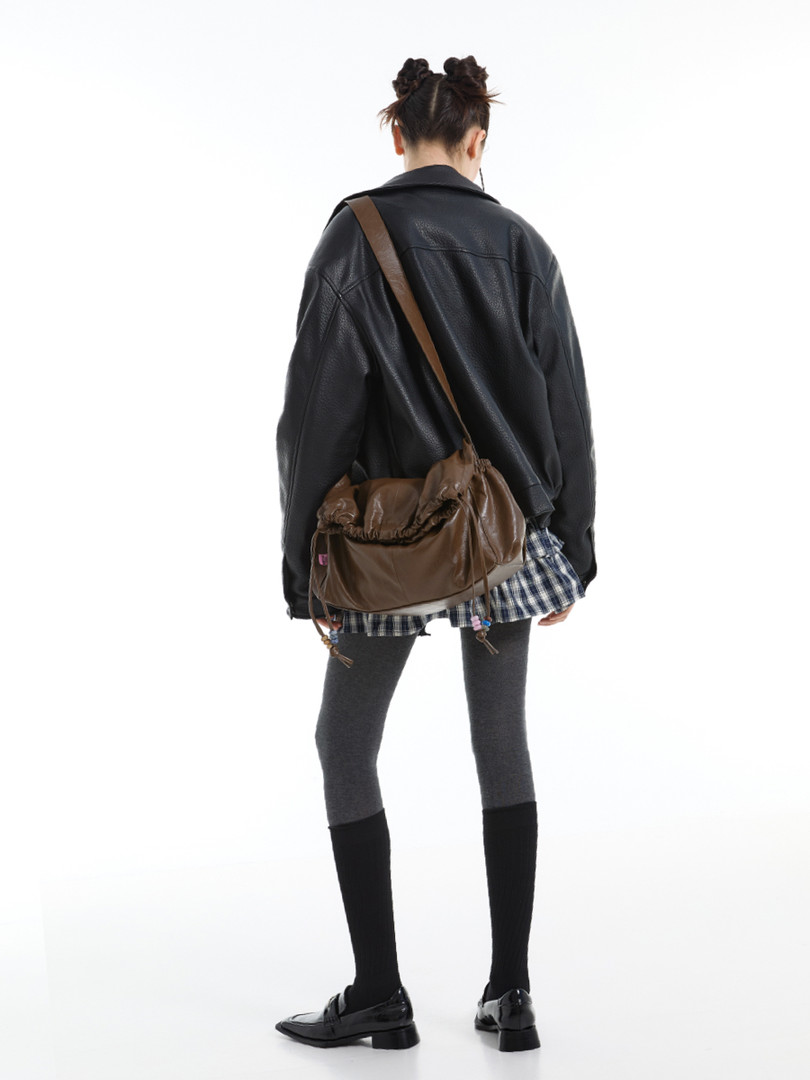Woman wearing a black jacket with a brown shoulder bag on a white background