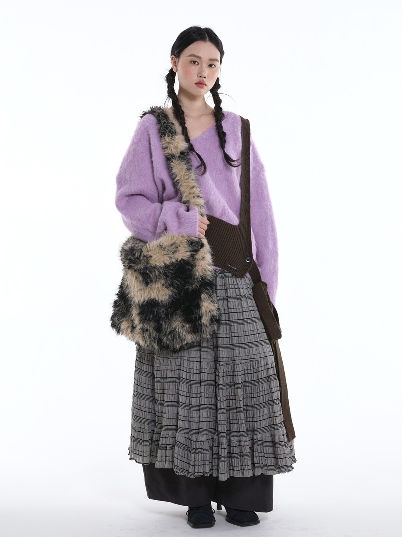 Fashion model wearing a lavender sweater with a layered skirt and furry shoulder bag