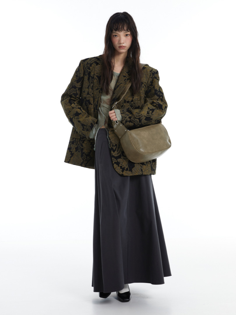 Model wearing a patterned oversized blazer with a long dark skirt and shoulder bag
