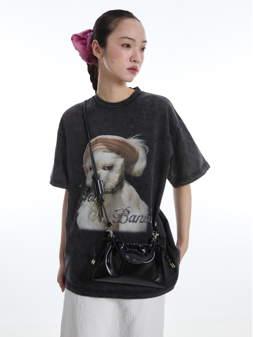 Model wearing a black oversized graphic T-shirt with a dog print and crossbody bag