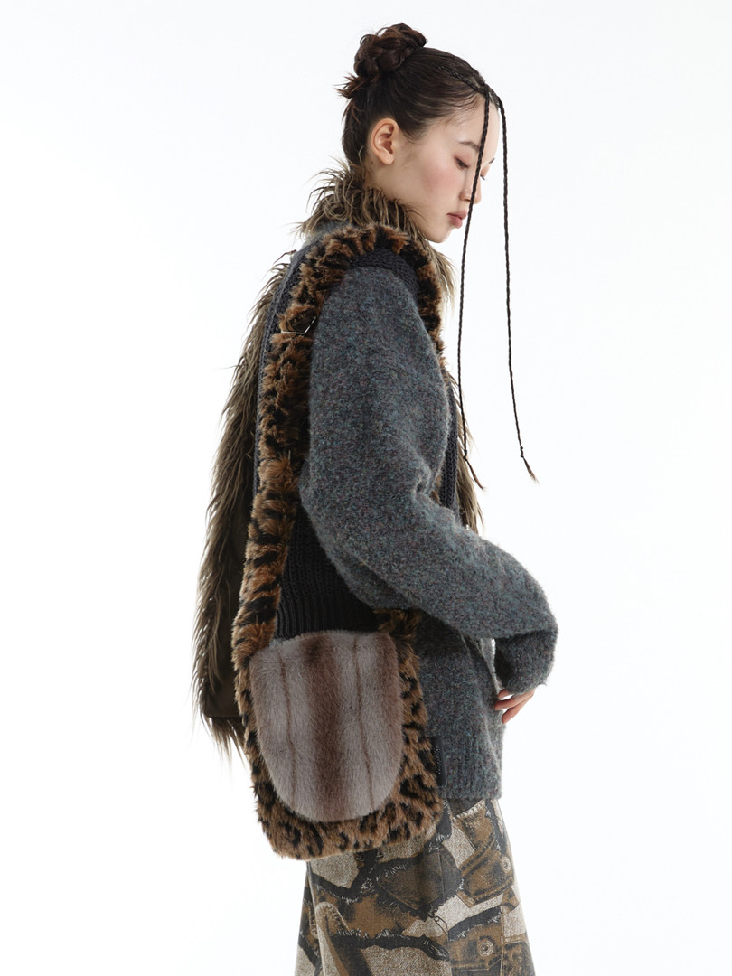 Model wearing a gray knit outfit with a long faux-fur vest