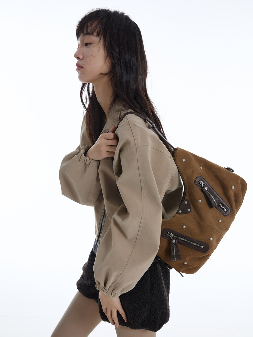 Brown suede backpack worn by a model with a beige jacket