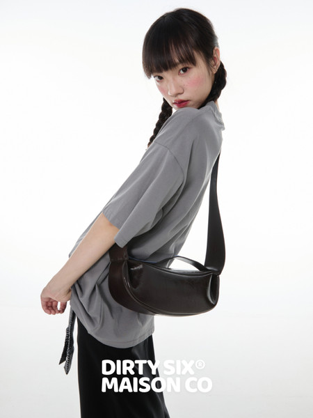 Model wearing an oversized gray T-shirt with a black shoulder bag