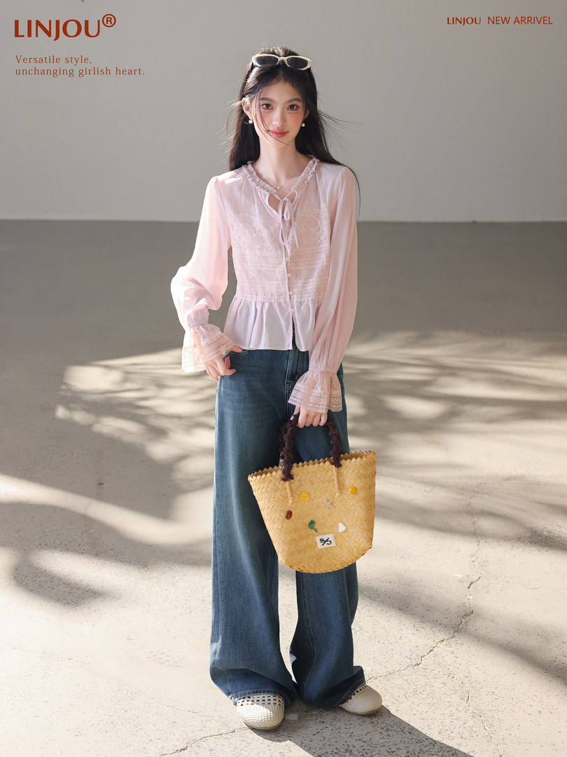 Model wearing a pastel lace blouse with wide-leg jeans and a woven tote bag