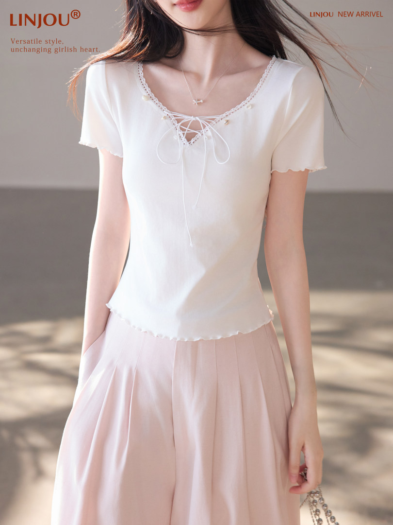 Woman wearing a white lace-up short sleeve top with a pink skirt