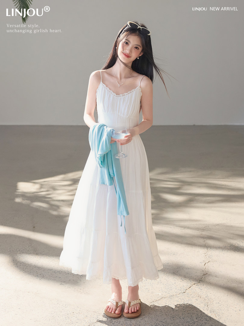 Woman wearing a white sleeveless midi dress with lace trim on a bright studio background