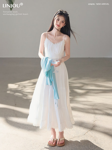 Woman wearing a white sleeveless midi dress with lace trim on a bright studio background