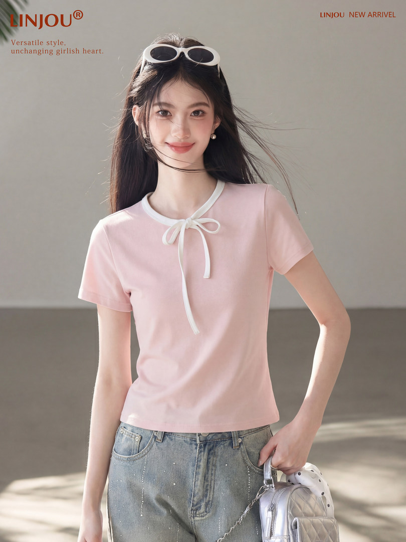 Model wearing a pink short-sleeve top with a white bow detail and jeans