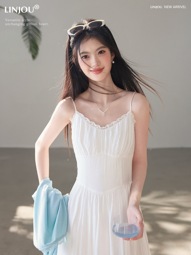 Woman wearing a white spaghetti-strap dress in a bright studio setting