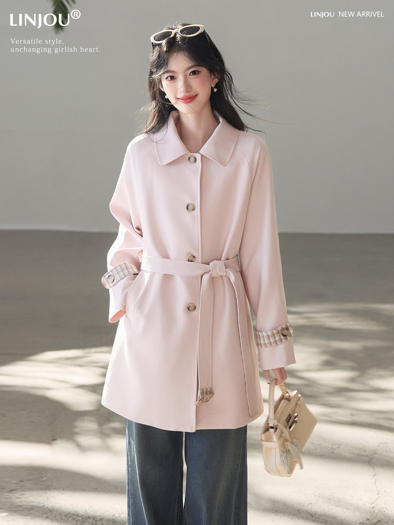 Light pink belted coat worn by a model with a handbag
