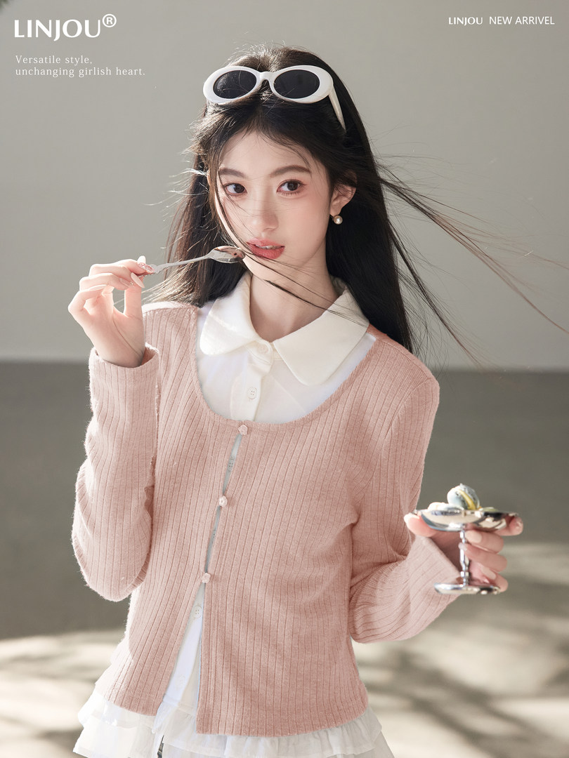 Pink ribbed cardigan worn over a white blouse on a model