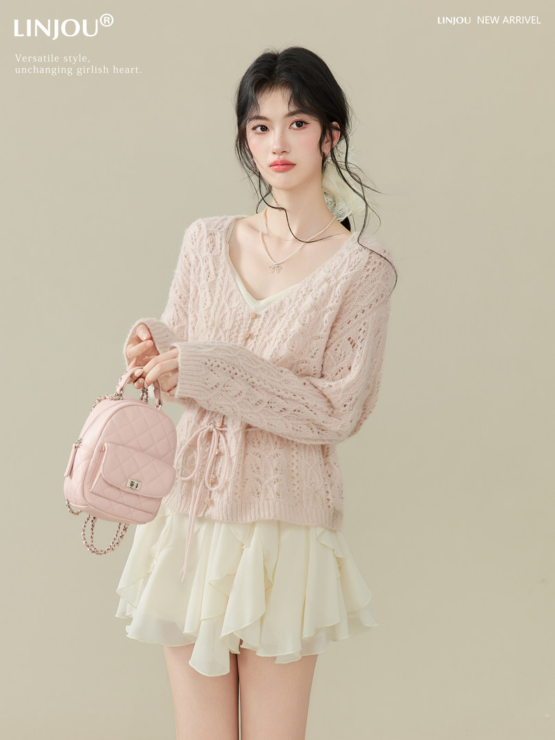 Model wearing a pale pink lace cardigan and cream ruffle skirt while holding a pink quilted mini backpack