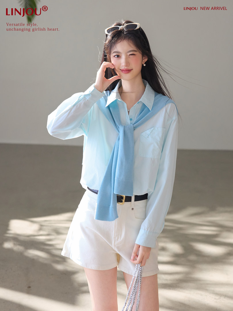 Model wearing a light blue sweater over a white shirt with white shorts