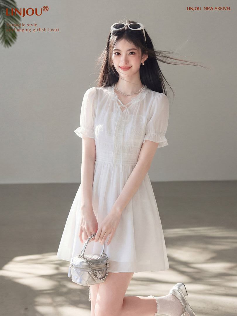 Woman wearing a white short-sleeve dress and holding a small silver handbag