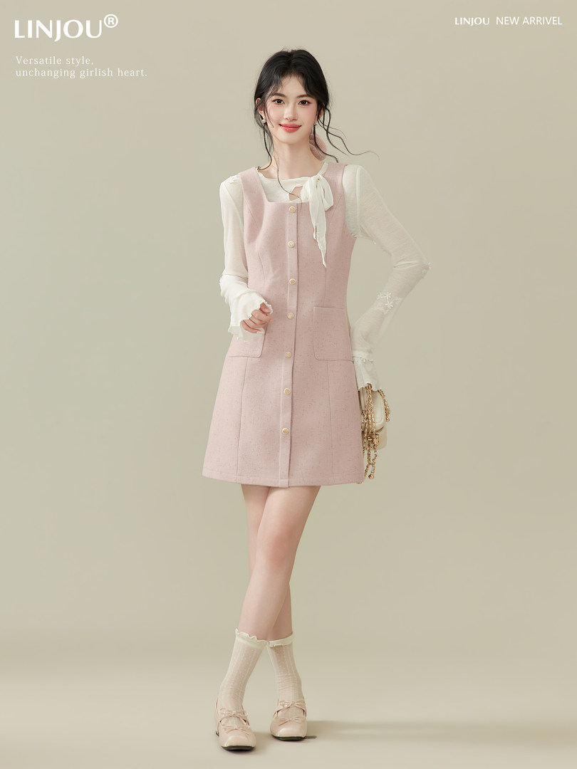 Model wearing a pink button-front pinafore dress over a white blouse