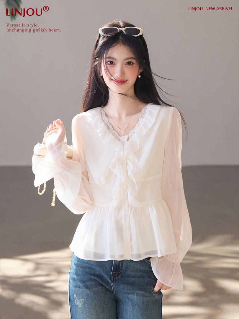 Model wearing a white ruffled sheer blouse with blue jeans