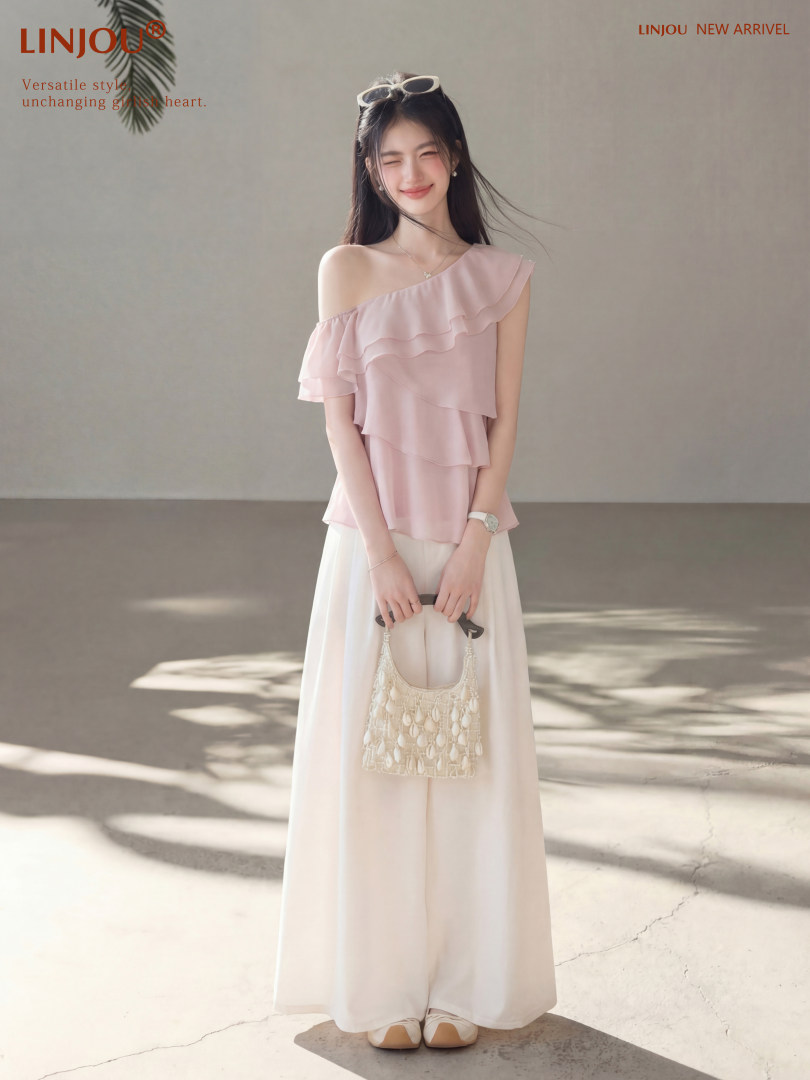 Model wearing a light pink off-shoulder ruffle top with wide-leg white pants
