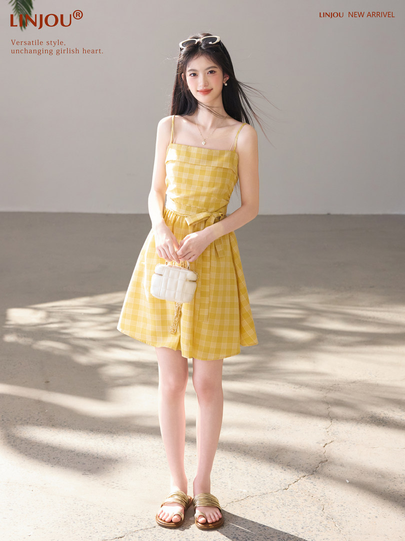 Model wearing a yellow plaid sleeveless dress with a small crossbody bag