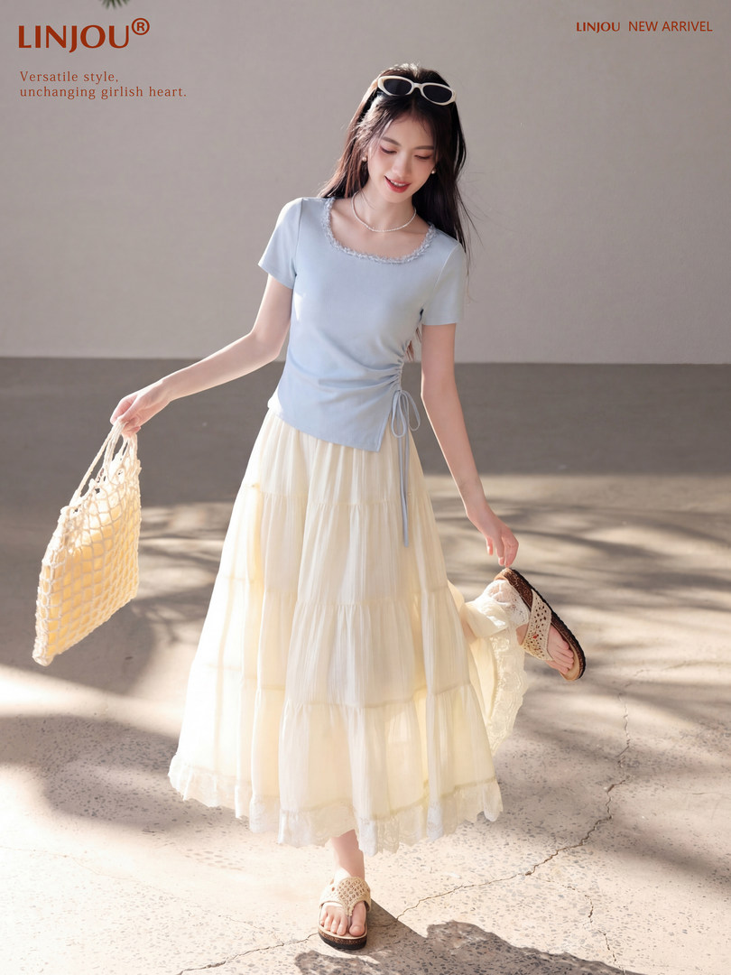 Model wearing a light blue top and cream tiered skirt with sandals and a woven bag