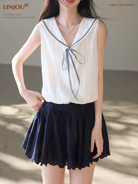 Model wearing a white sleeveless sailor-collar top with navy trim and a navy skirt