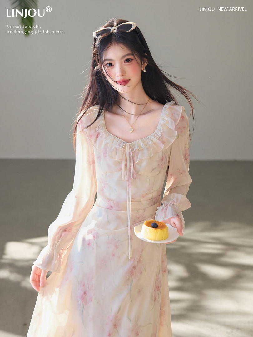 Model wearing a light floral chiffon dress with ruffled neckline and long sleeves