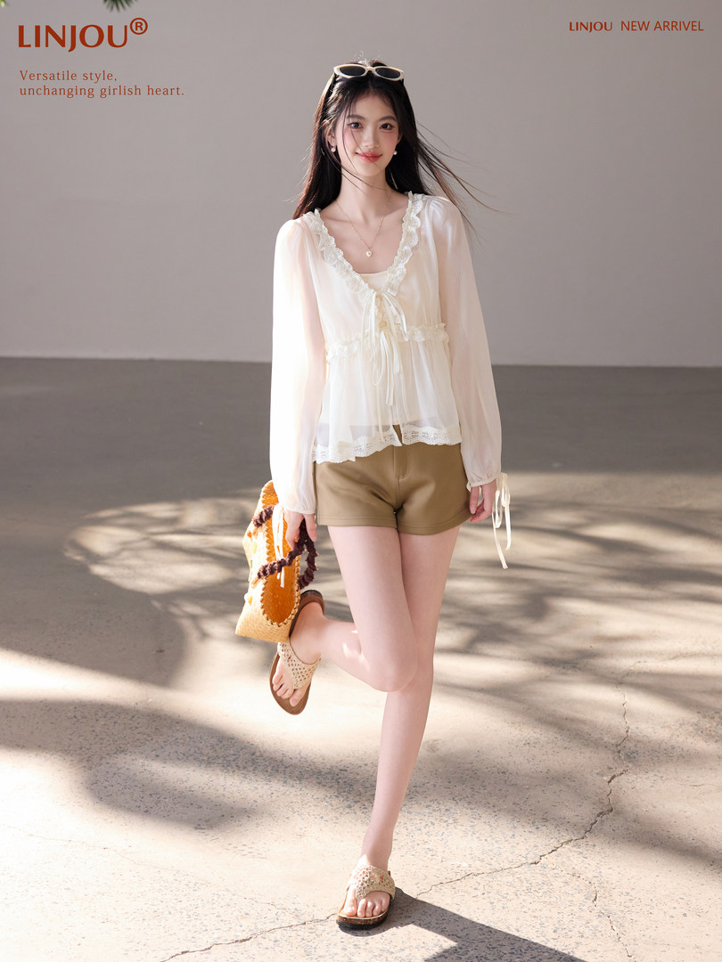 Model wearing a white lace-trim blouse with tan shorts and sandals