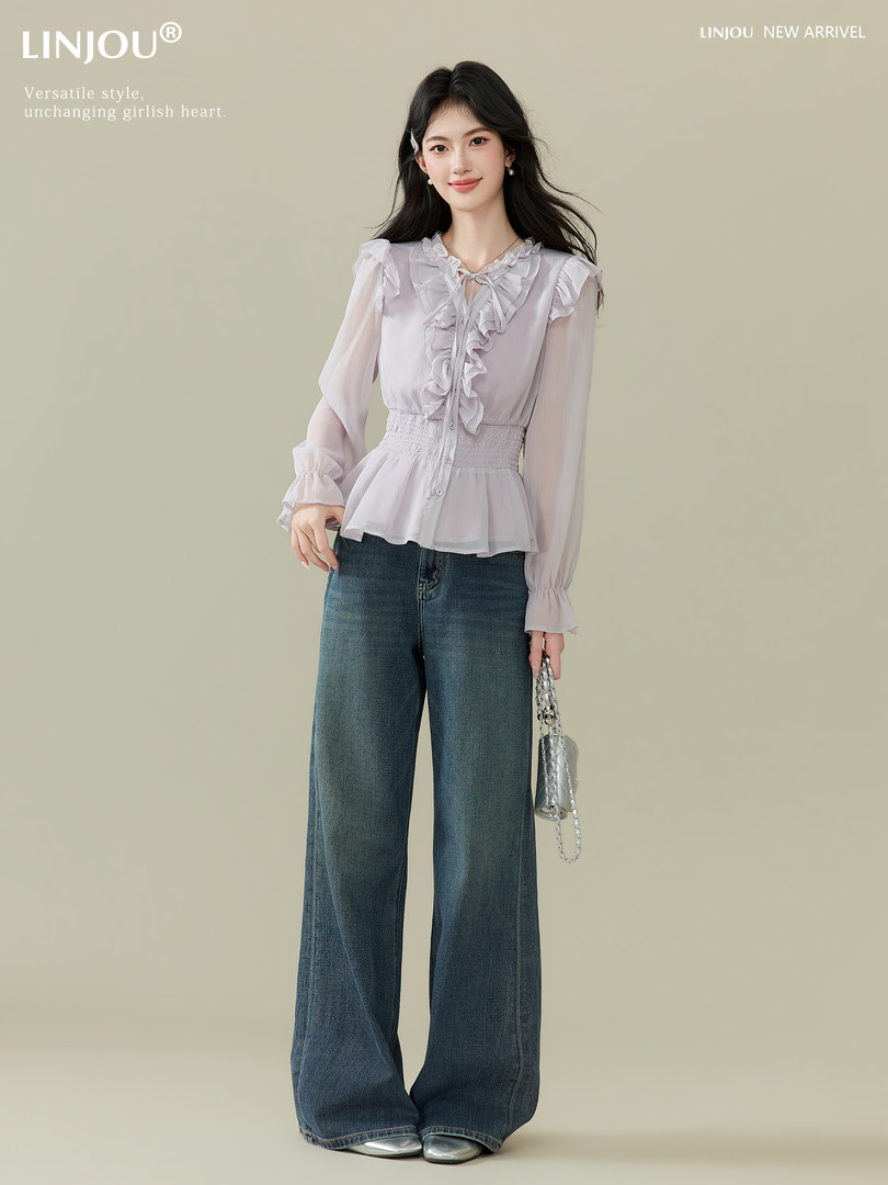 Female model wearing a ruffled light blouse with wide-leg jeans and a small handbag