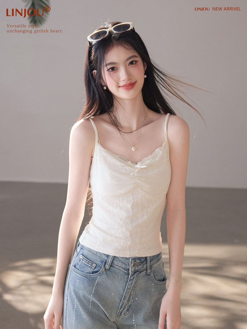 Model wearing a white lace camisole top with blue jeans