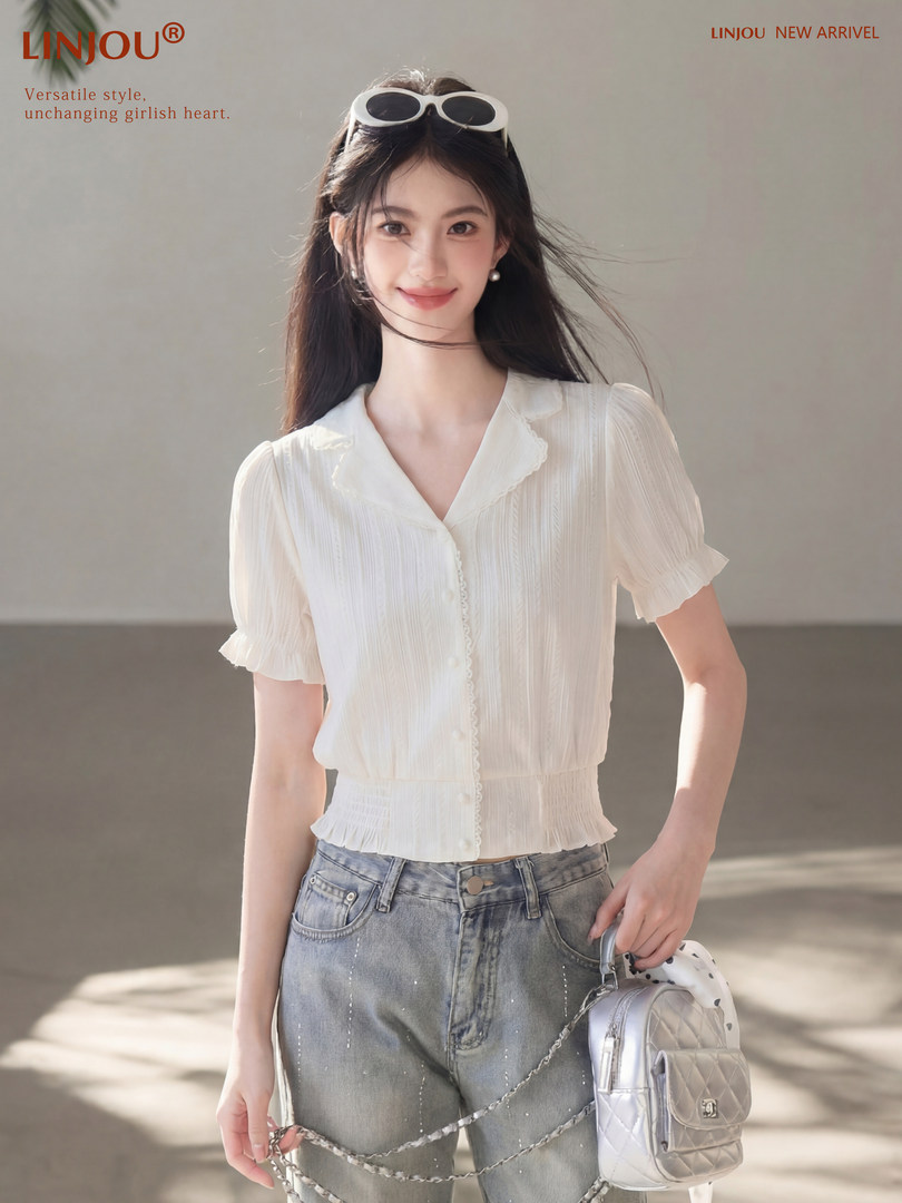 Model wearing a white short-sleeve blouse with jeans and a small handbag