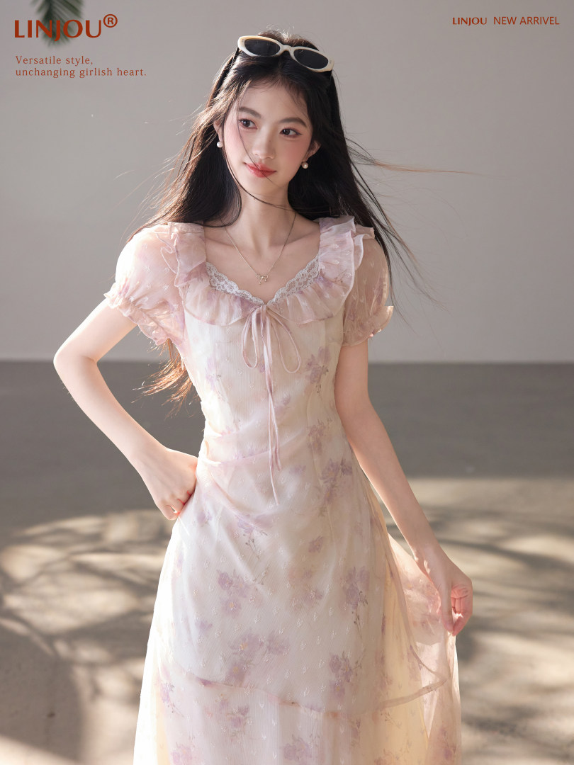 Model wearing a light pink floral ruffled dress with short sleeves