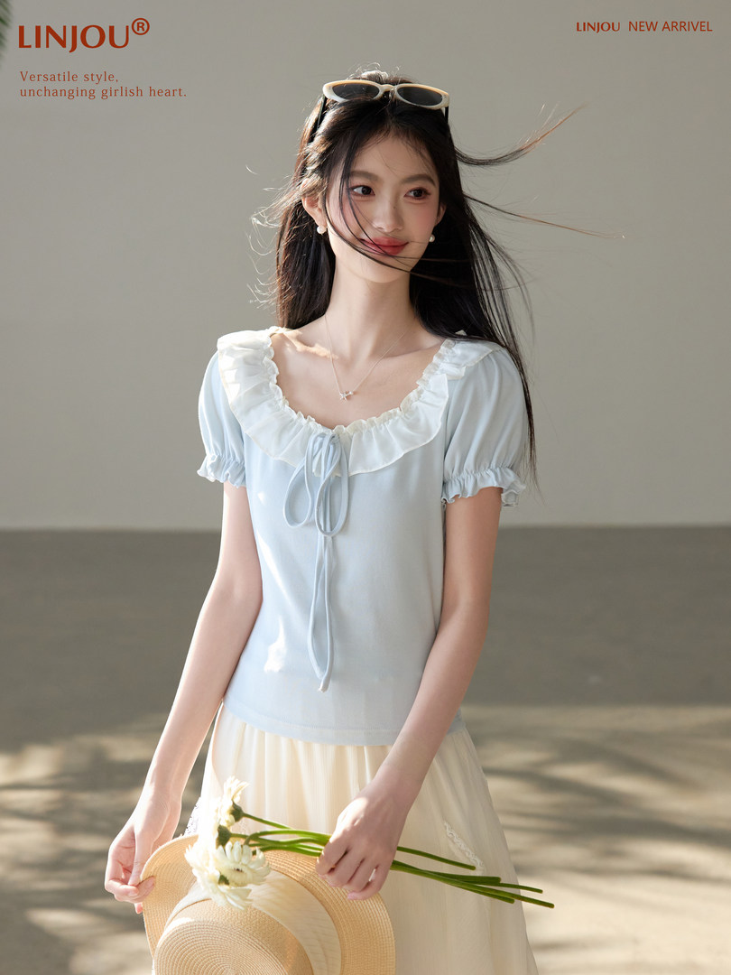 Young woman wearing a light blue ruffled short-sleeve top with a cream skirt