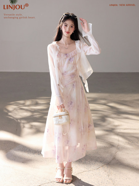 Woman wearing a light pink floral dress with a sheer white cover-up and handbag