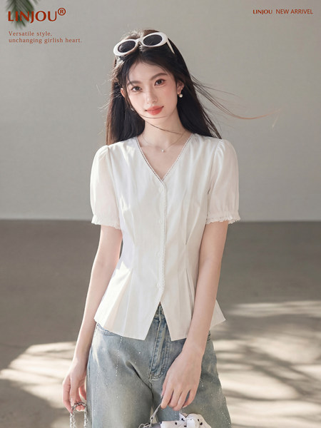 Woman wearing a white short-sleeve blouse with blue jeans