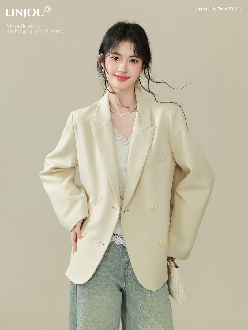 Model wearing a cream double-breasted blazer with jeans on a neutral background