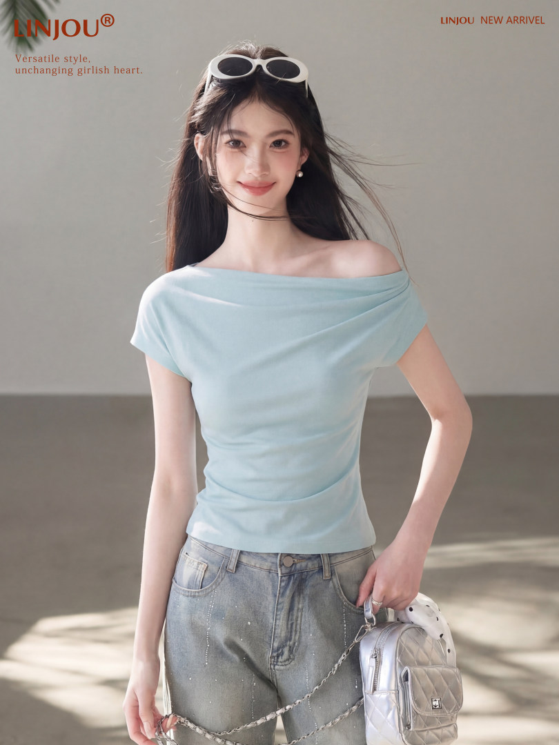 Woman wearing a light blue off-shoulder top with jeans and a small silver backpack
