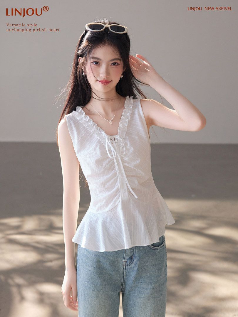 Model wearing a white ruffled sleeveless top with blue jeans