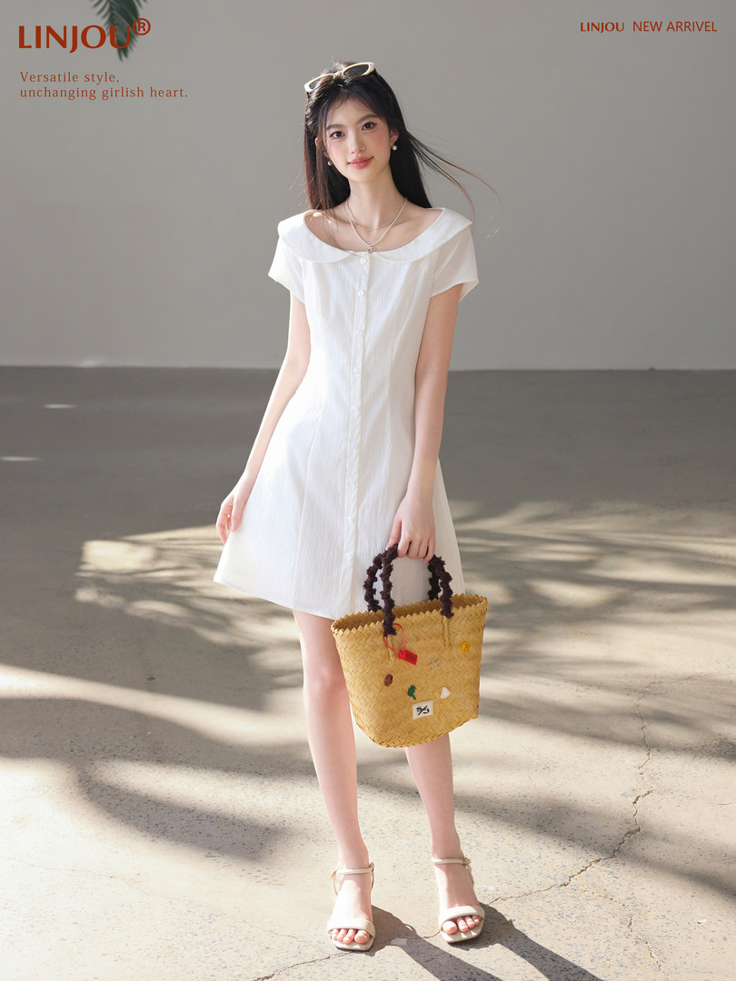Woman wearing a white short-sleeve dress and holding a woven tote bag