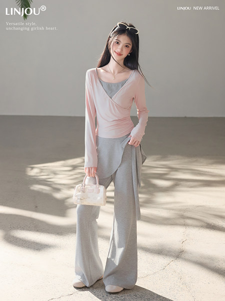 Model wearing a pink wrap top and gray wide-leg lounge set while holding a small handbag