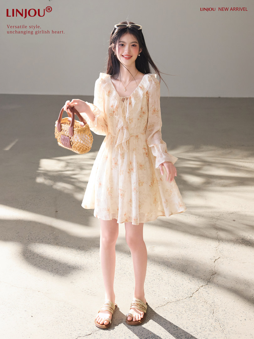 Model wearing a cream floral mini dress with sandals and a woven handbag
