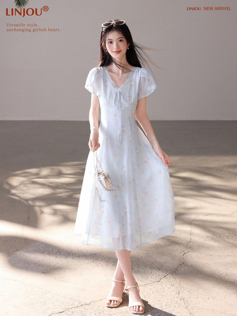 Model wearing a light blue midi dress with lace trim and short sleeves
