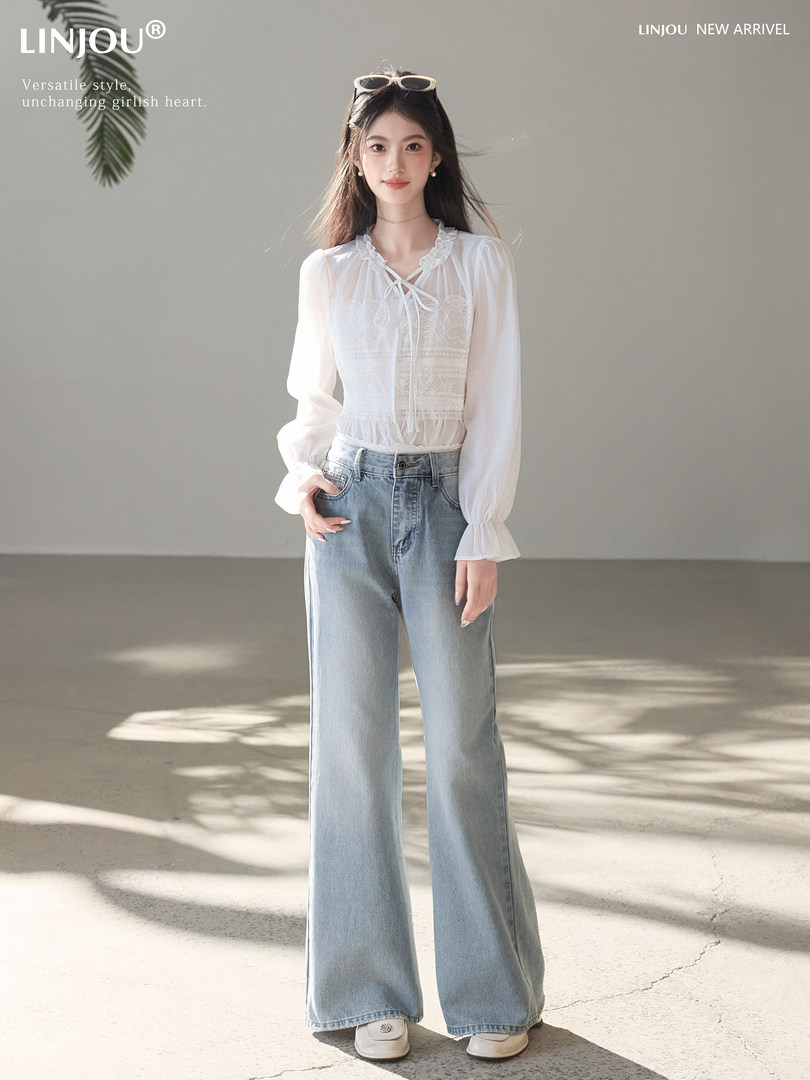 Model wearing a white sheer blouse and light blue wide-leg jeans