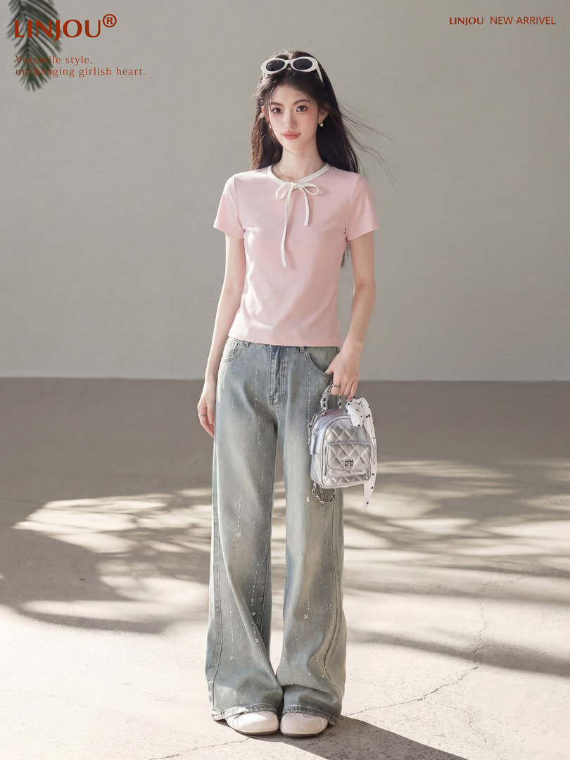 Model wearing a pink short-sleeve bow-top with wide-leg jeans and a silver mini backpack