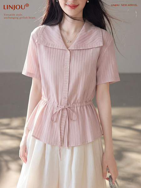 Model wearing a light pink short-sleeve button-up blouse with drawstring waist