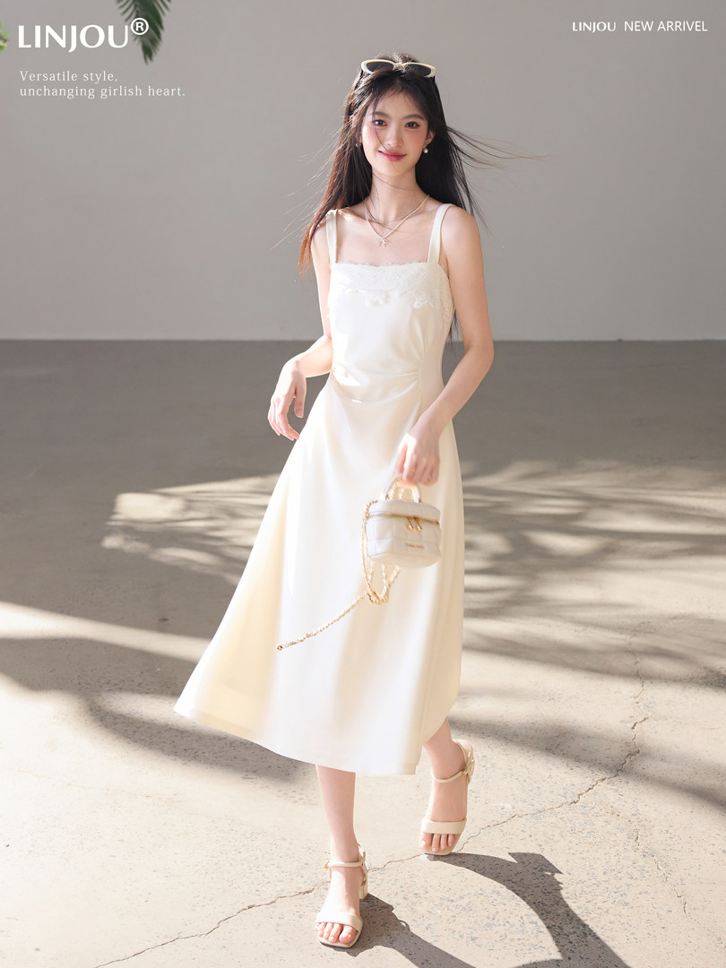 Woman wearing a white sleeveless midi dress with beige sandals and a small handbag
