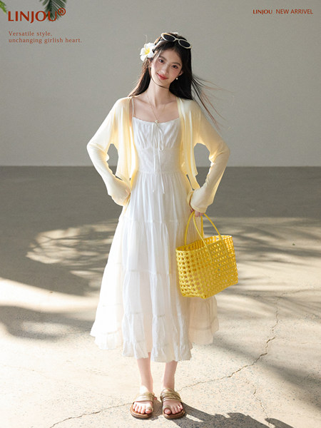 Model wearing a white midi dress with a light yellow cardigan and woven yellow tote bag