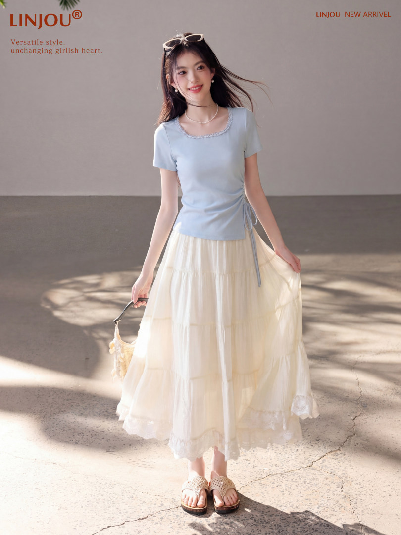 Model wearing a light blue short-sleeve top with a cream tiered skirt
