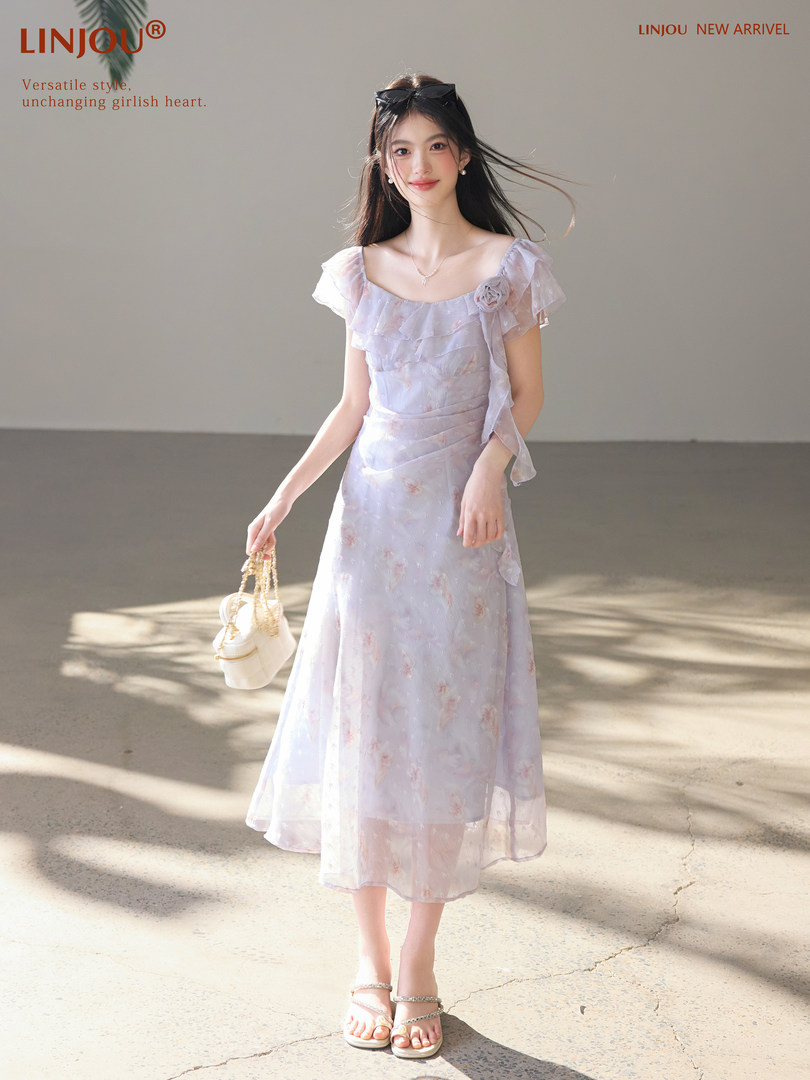 Model wearing a light pastel floral midi dress with sandals and a small handbag
