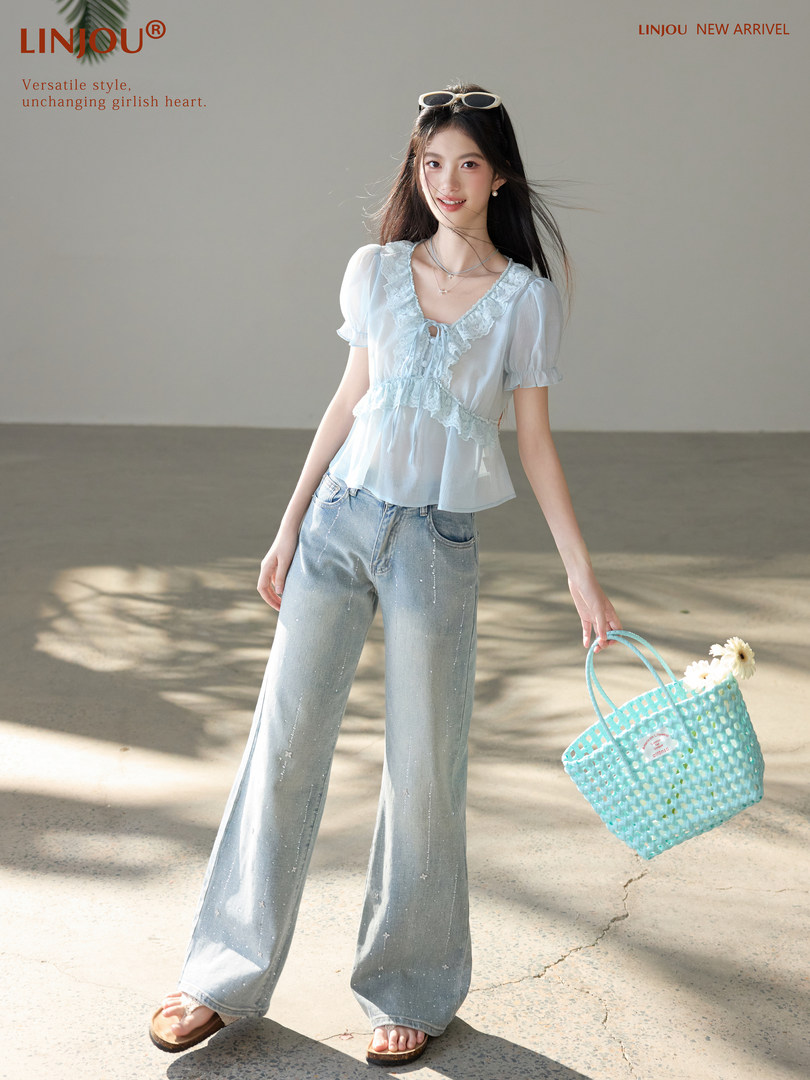 Model wearing a light blue lace-trim top with wide-leg jeans and a woven tote bag