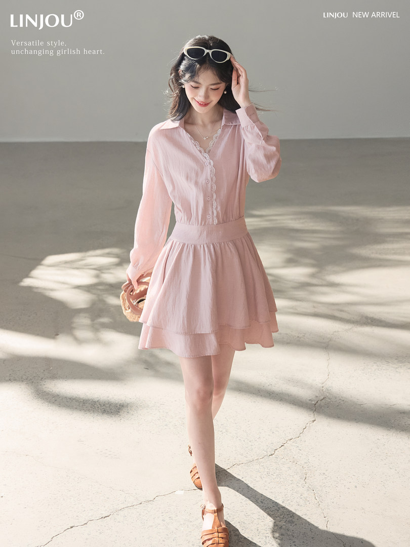 Model wearing a light pink long-sleeve button-front dress with a layered skirt