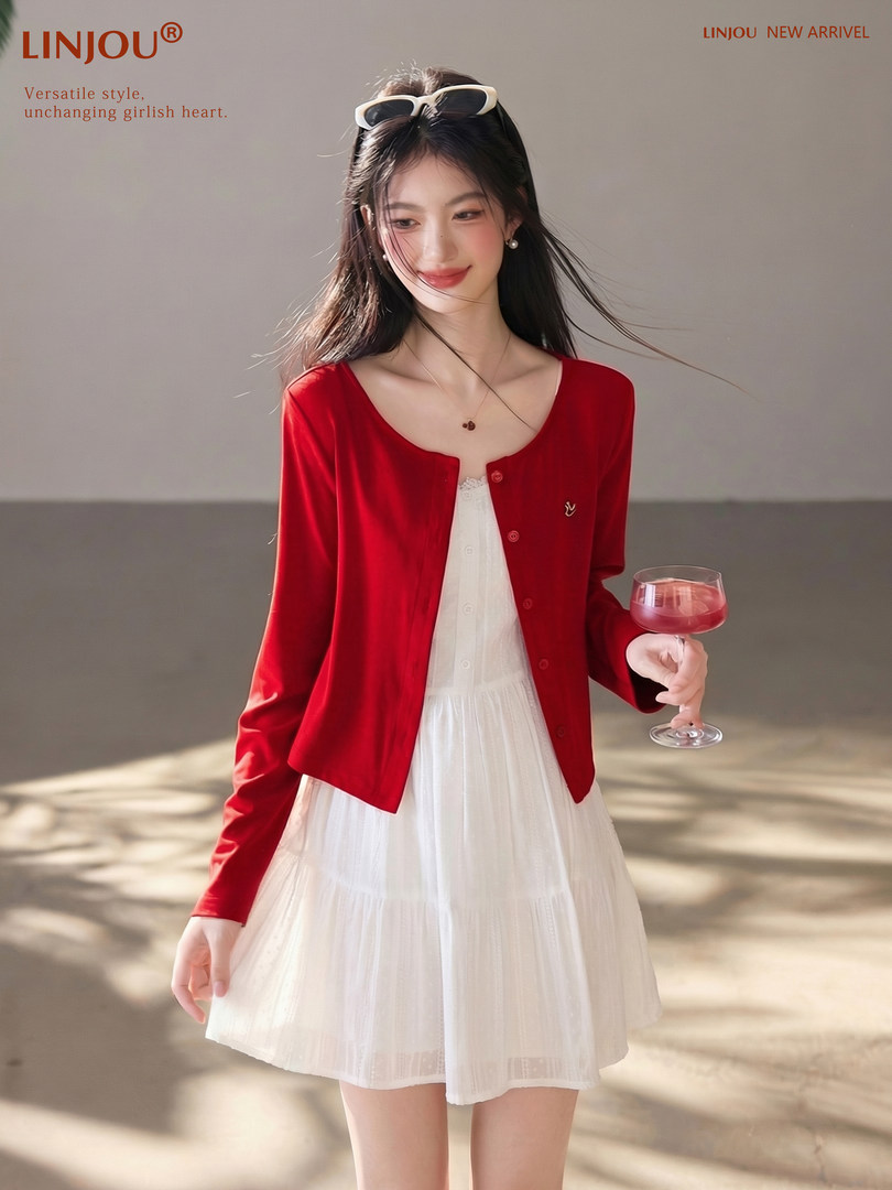Woman wearing a red cardigan over a white dress, posed as a fashion product photo